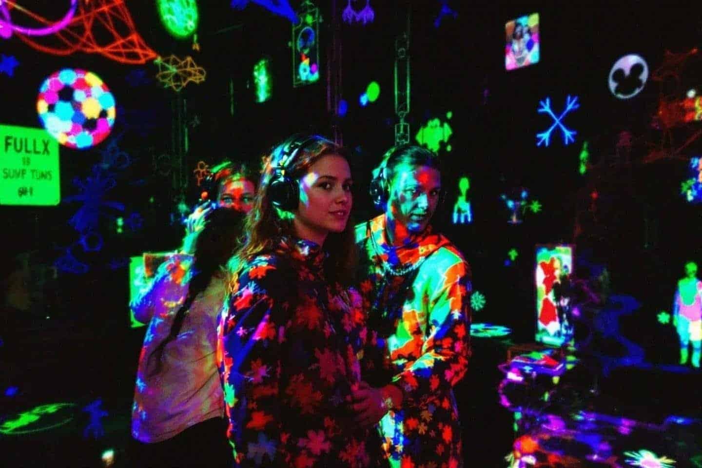 Personnes dans un environnement néon multicolore avec écouteurs